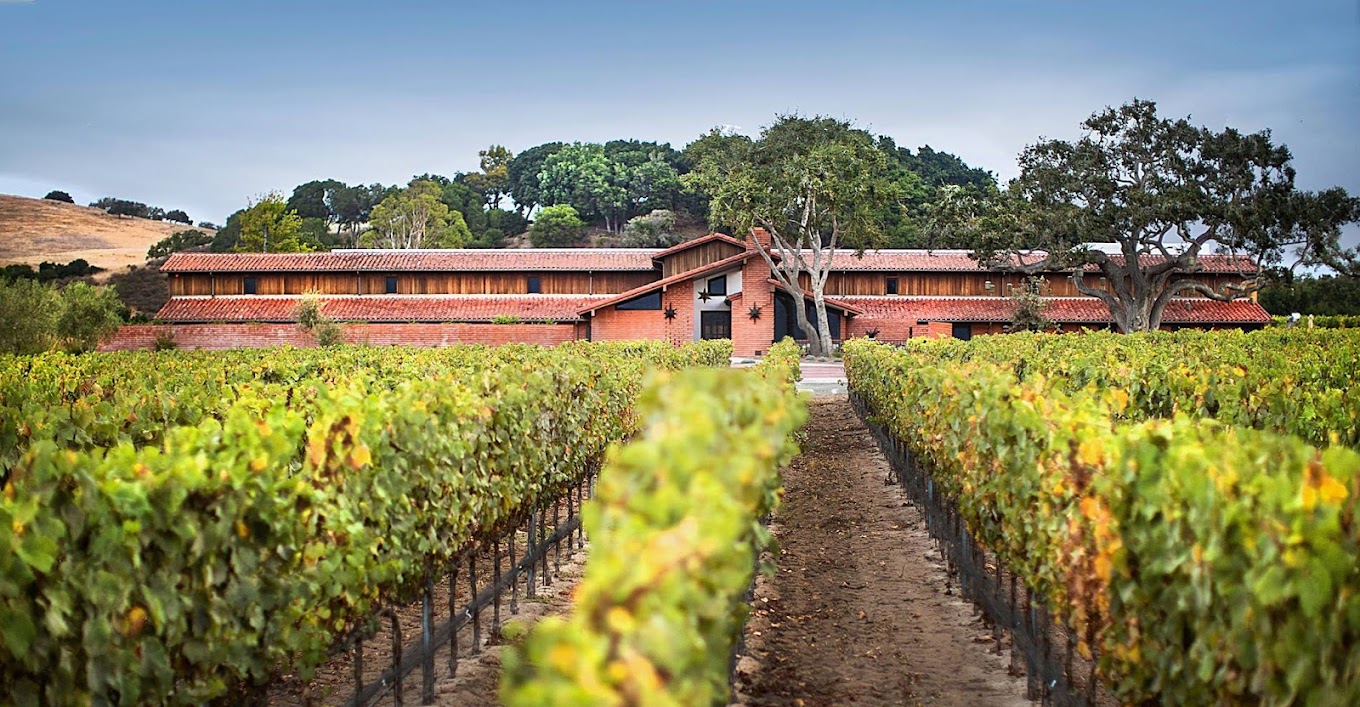 Front view of Brick Barn Wine Estate in Santa Ynez Valley with bright green sweeping view of the vineyard