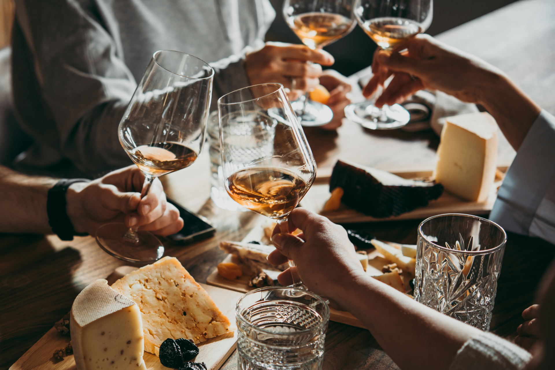 A small group of friends clinking wine glasses during a Santa Barbara wine and cheese pairing