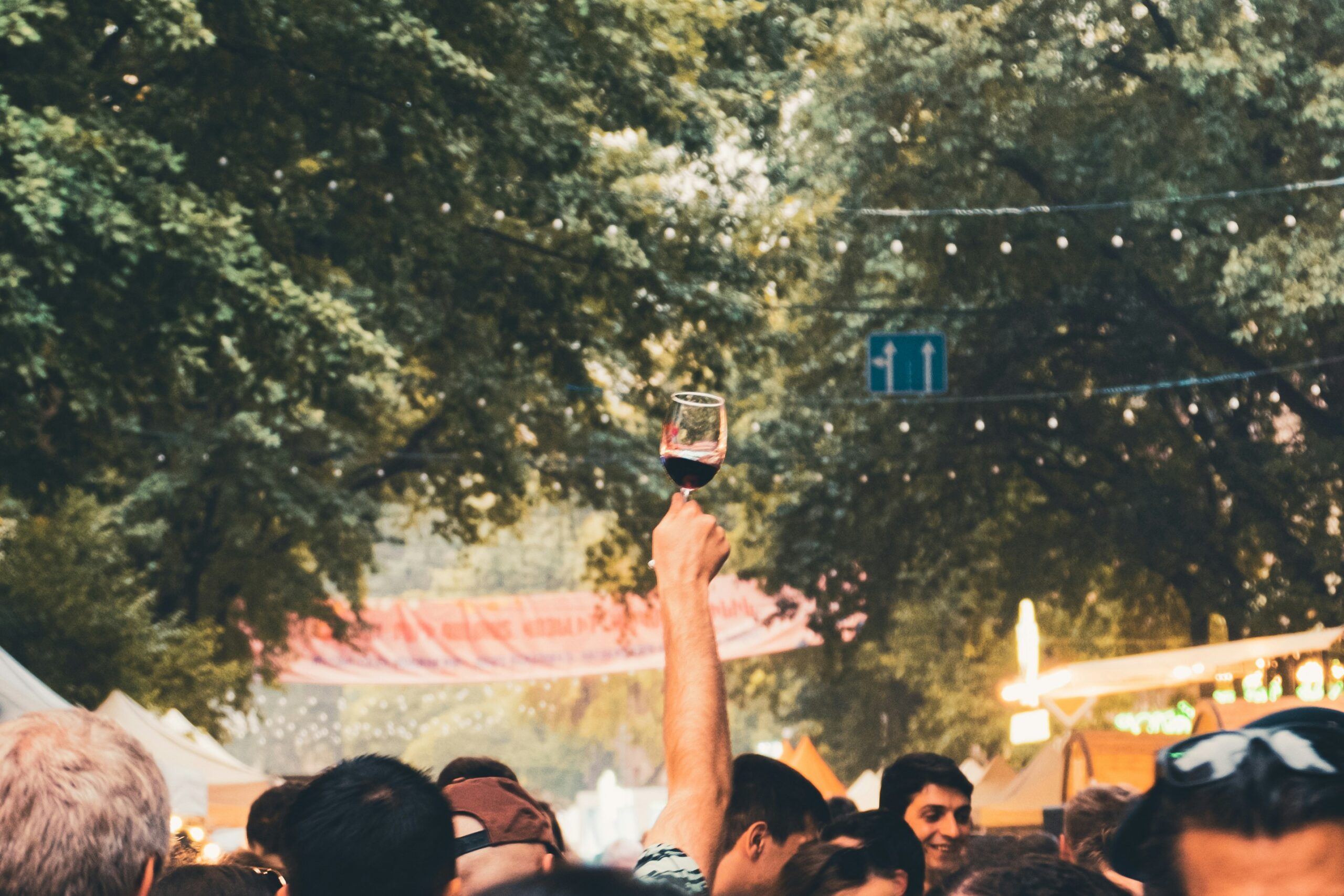 A hand in a crowd raising a glass in the air at a Buellton wine festival